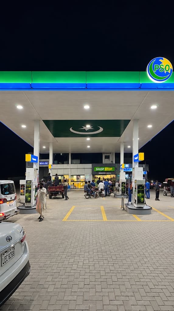 Mashaal PSO Station night view with illuminated canopy, crescent on roof, digital fuel dispensers, and Shop Stop in Raiwind, Lahore
